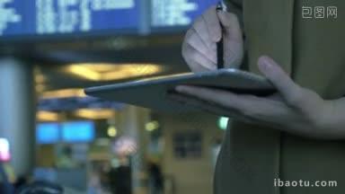 倾斜的镜头，一个女人与平板电脑与<strong>航班</strong>时刻表背景，她用钢笔打字信息
